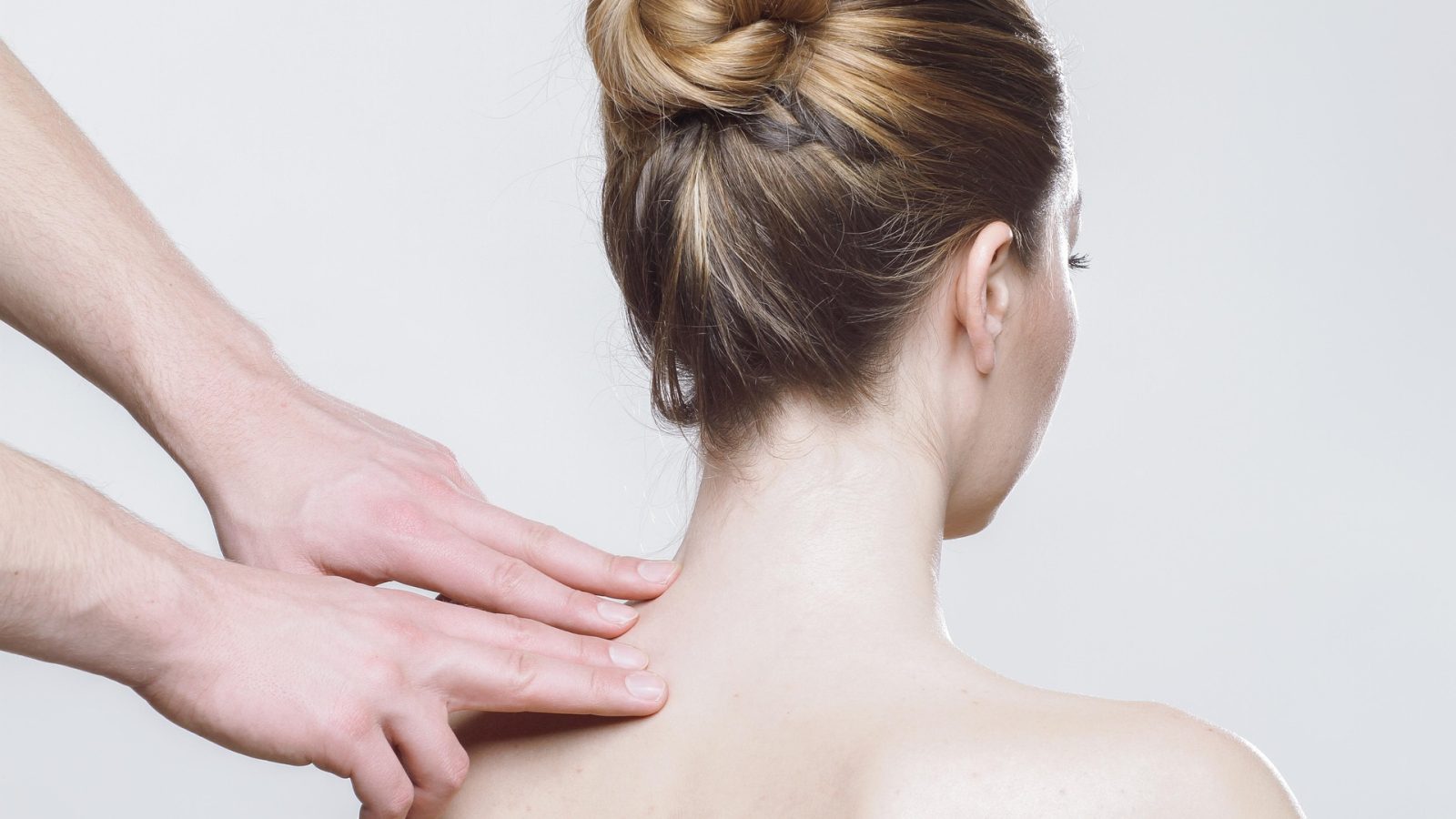 A massage being given to the neck and shoulder, hands working into bare skin